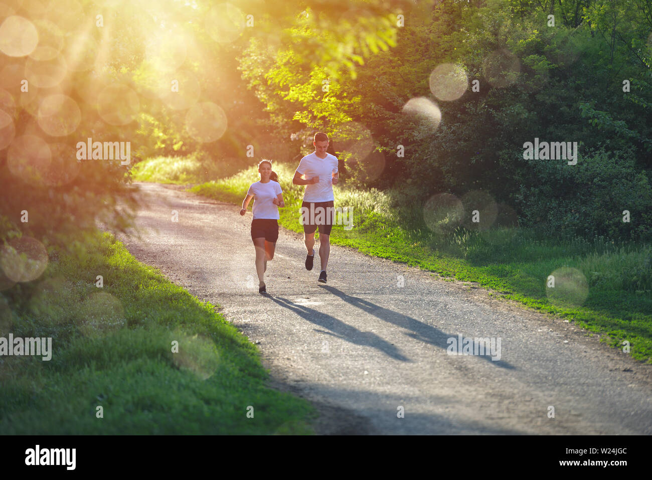 Young people jogging and exercising in nature, in morning sunrise warm light Stock Photo