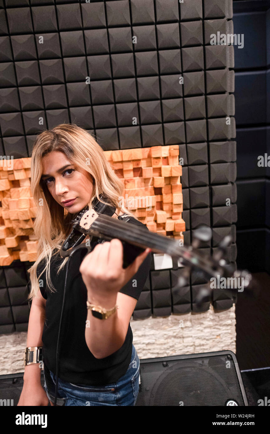 Portrait of a musician posing with electric violin in a music studdio