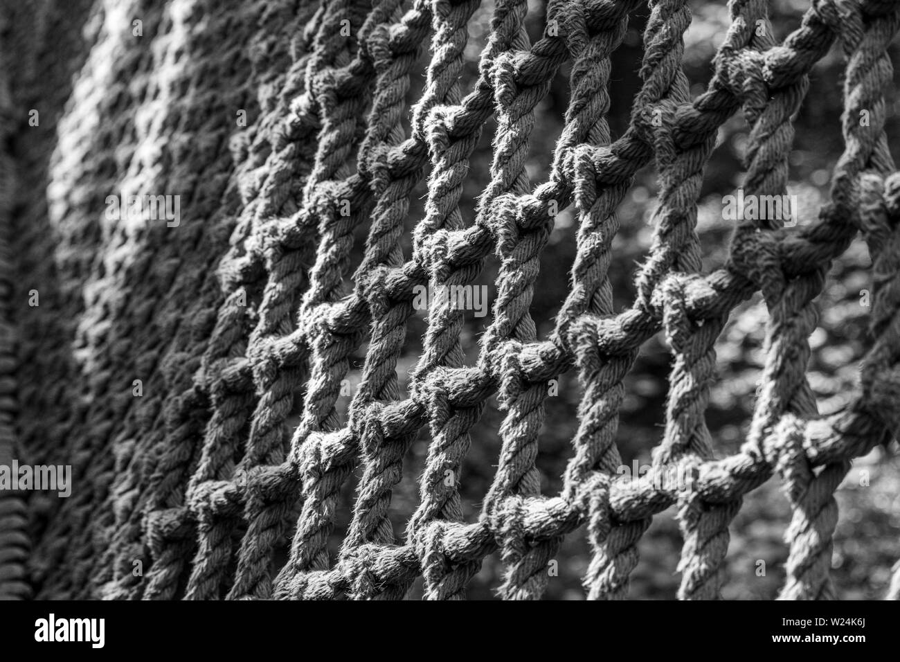 Black and white closeup view of ropes tied to form netting in an abstract pattern. Stock Photo