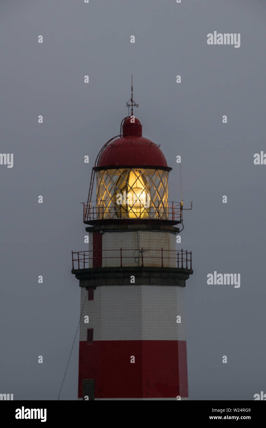 lighthouse with the light bulb on at dusk Stock Photo