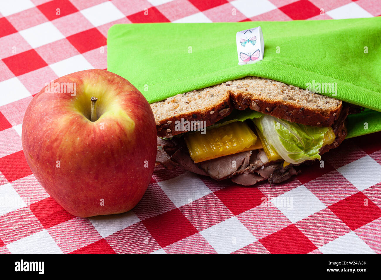 An apple and a sandwich in a environmentally friendly, homemade