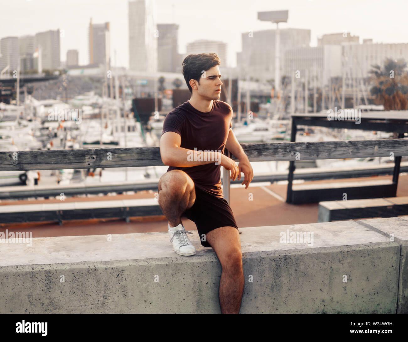 Young athletic man after running at park with skyscrapers background Stock Photo