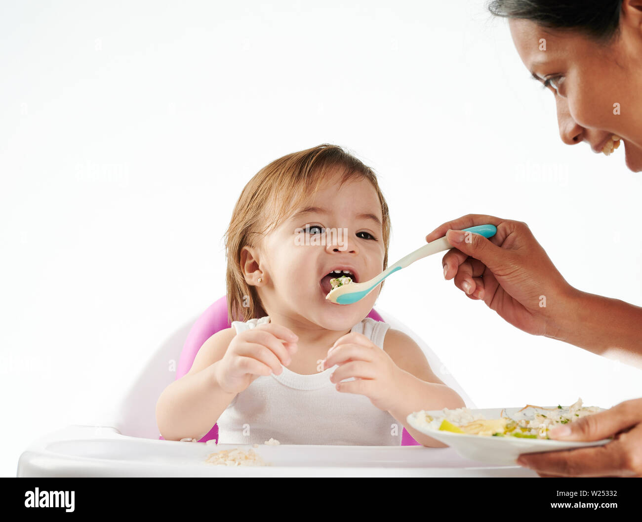 Lunch of baby girl. Mom feeding small child isolated Stock Photo