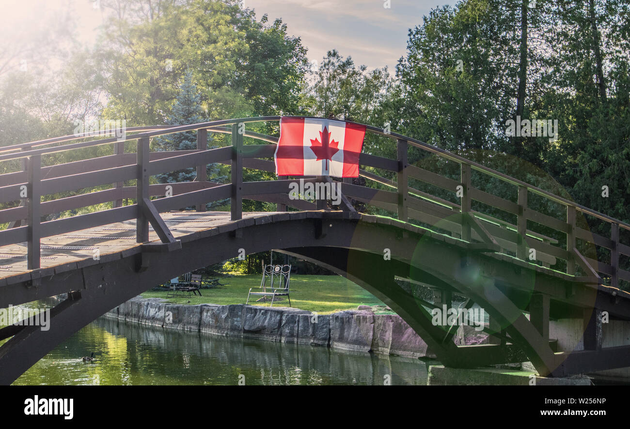 At sunset the sunbeams are crossing the Canadian flag on a wooden bridge in Stratford. Stock Photo