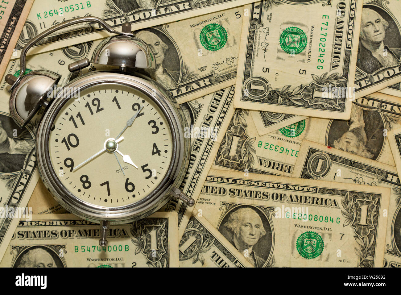 Alarm clock on carpet of dollar bills, time is money Stock Photo Alamy