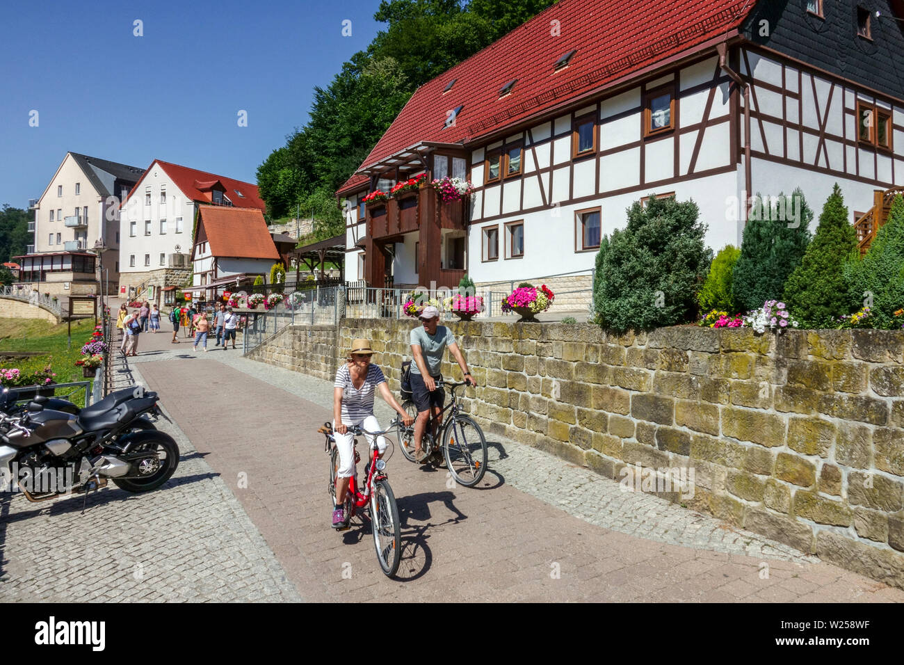 Tourists on bicycles Kurort Rathen Half-timbered houses Saxon Switzerland Germany Cycling Elbe valley buildings People Biking Bikes Couple Bikers Stock Photo