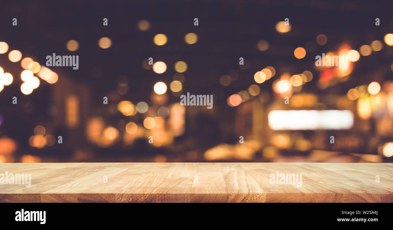 Wood table top (Bar) with blur light bokeh in dark night cafe