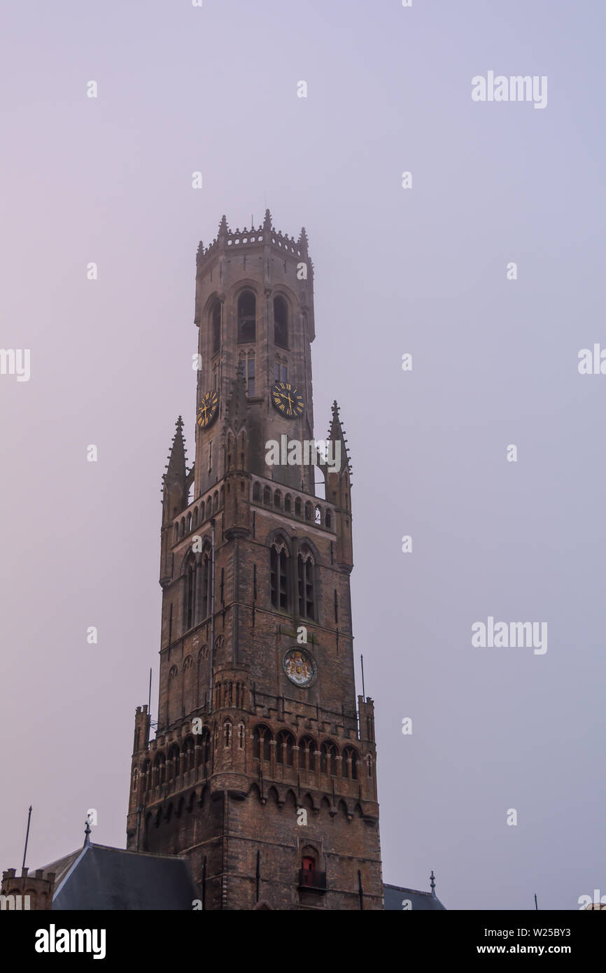 Belfry of Bruges, the medieval bell tower  in slight morning fog. The 83 meter high belfry or hallstower (halletoren) is Bruges' most well-known landm Stock Photo