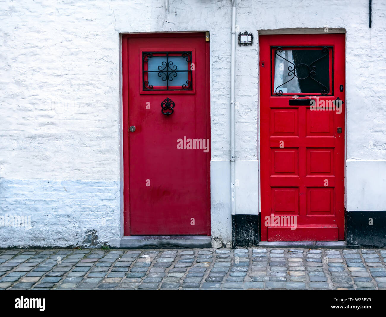 Two Red Wooden Front Doors In The White Brick Wall Two Vintage Red Doors With Window At The Top Stock Photo Alamy