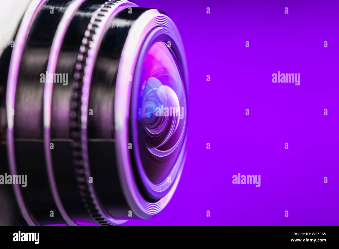 Camera lens and dark purple backlight. Side view of the lens of camera