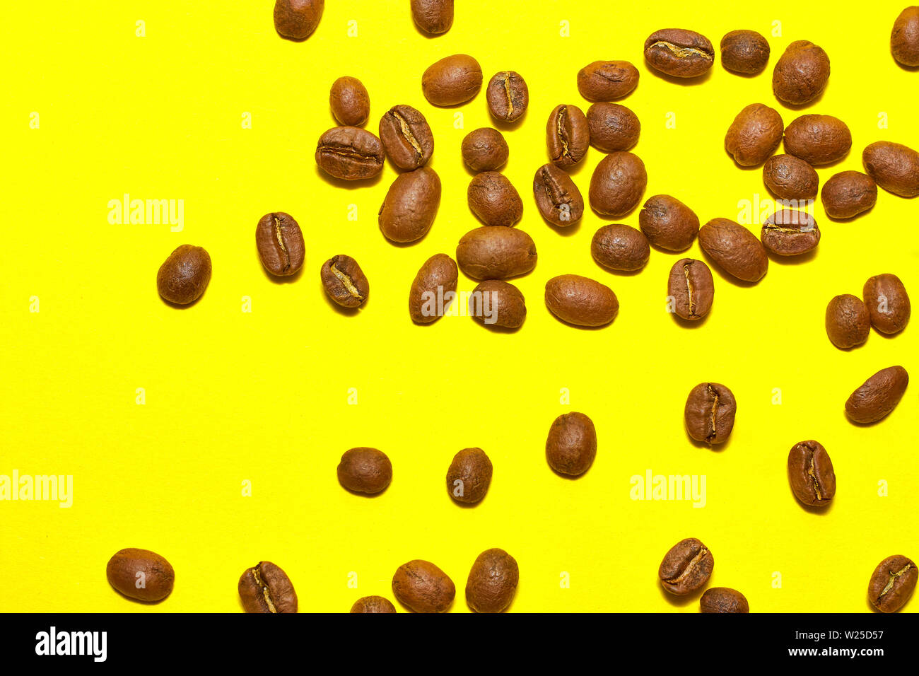 Coffee beans isolated on the yellow background. Joyful minimal coffee-theme with copy space Stock Photo