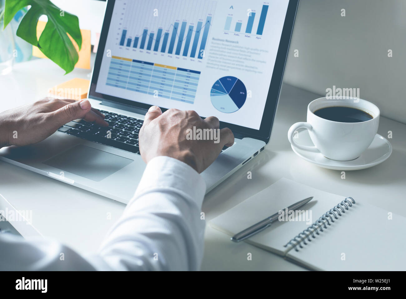 Young businessman typing computer laptop with graph chart for work Stock Photo