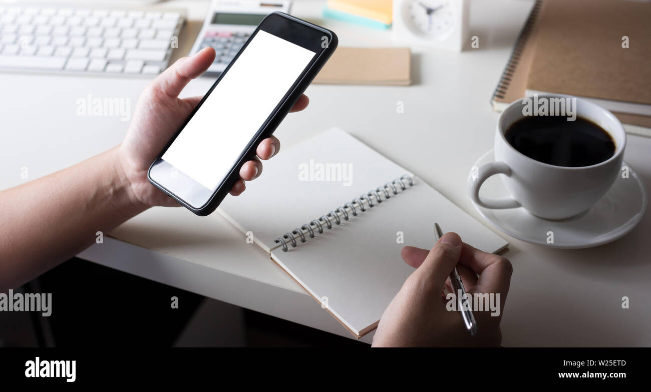 Young woman using (touch screen) smartphone for work with worktable Stock Photo