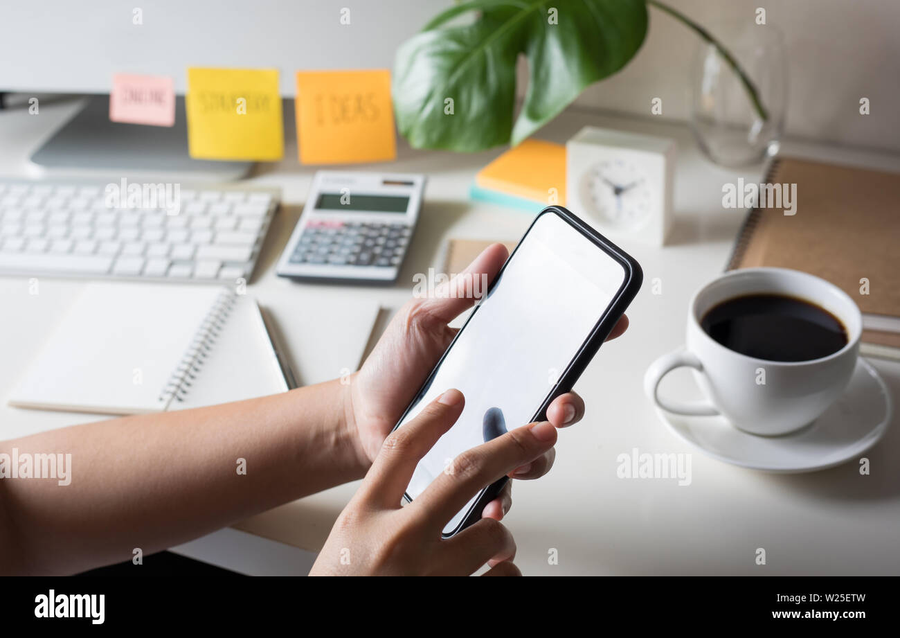 Young woman using (touch screen) smartphone for work with worktable Stock Photo