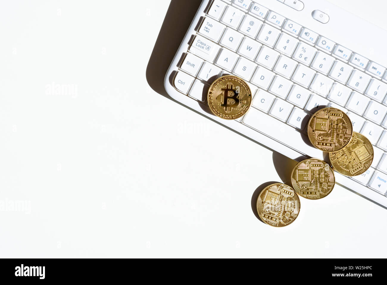 Top view of gold coins with  bitcoin lying on white computer keyboard and white table. Concept of finance and business in internet. Trade virtual cryp Stock Photo