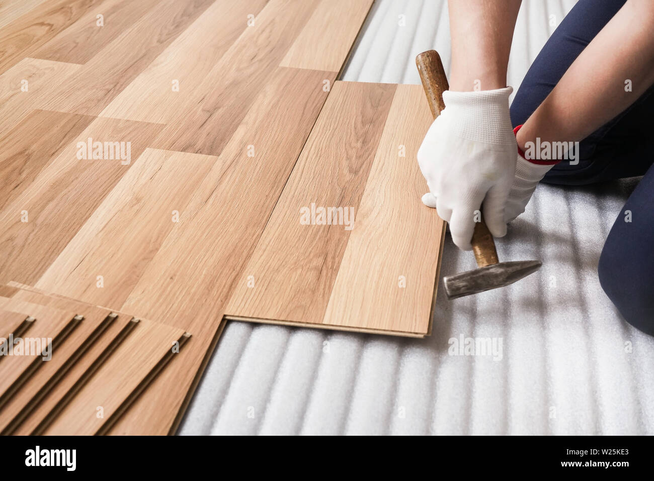 Installing laminated floor, detail on man hands fixing one tile with