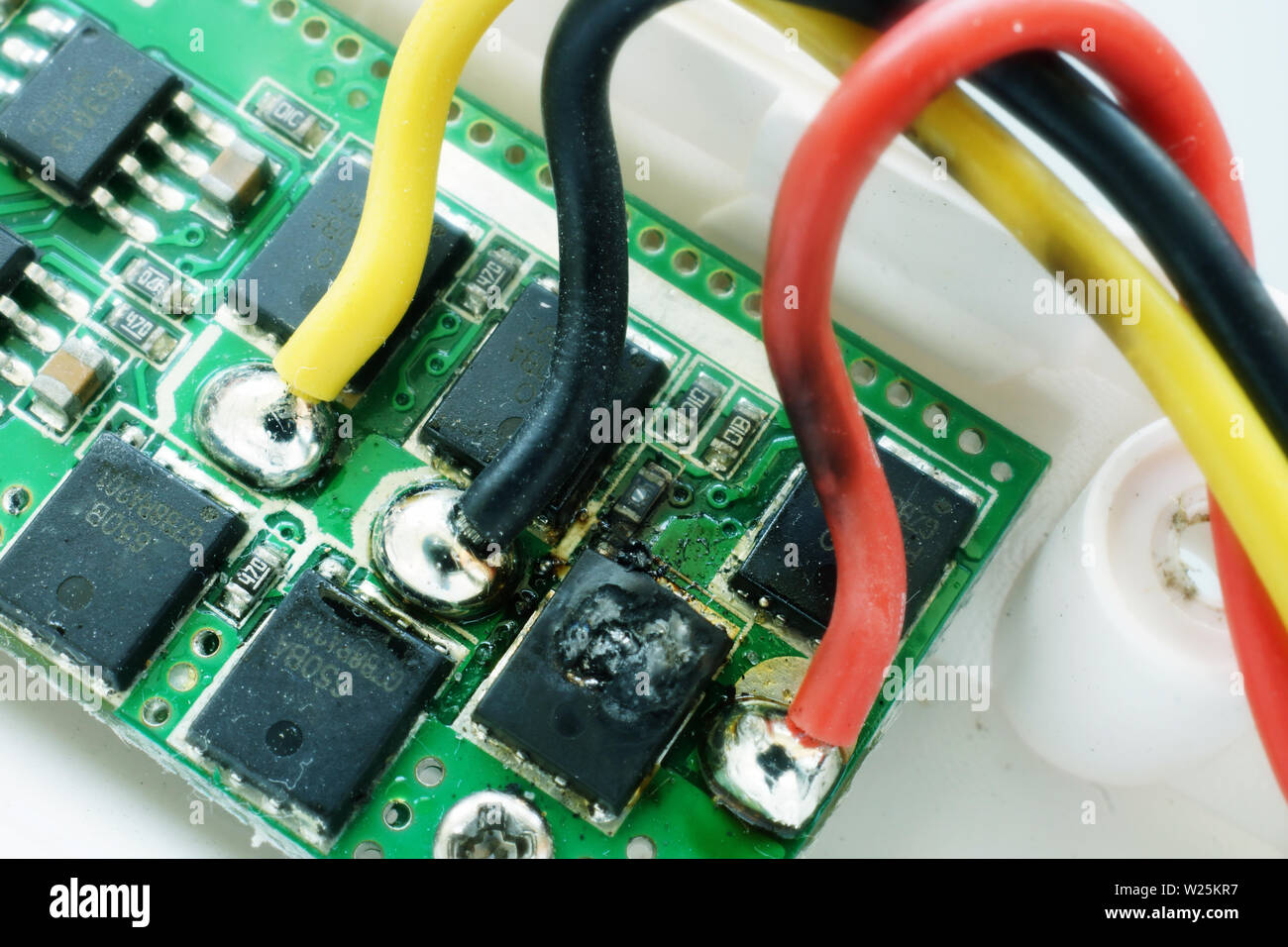 Microcircuit with a burnt-out microchip. Breakdown of electronic equipment. Stock Photo