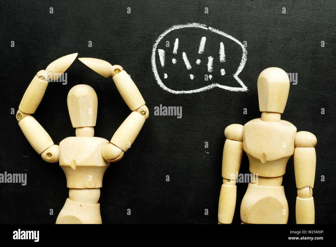 Abuse and bullying in communication. Two wooden figurines. Stock Photo