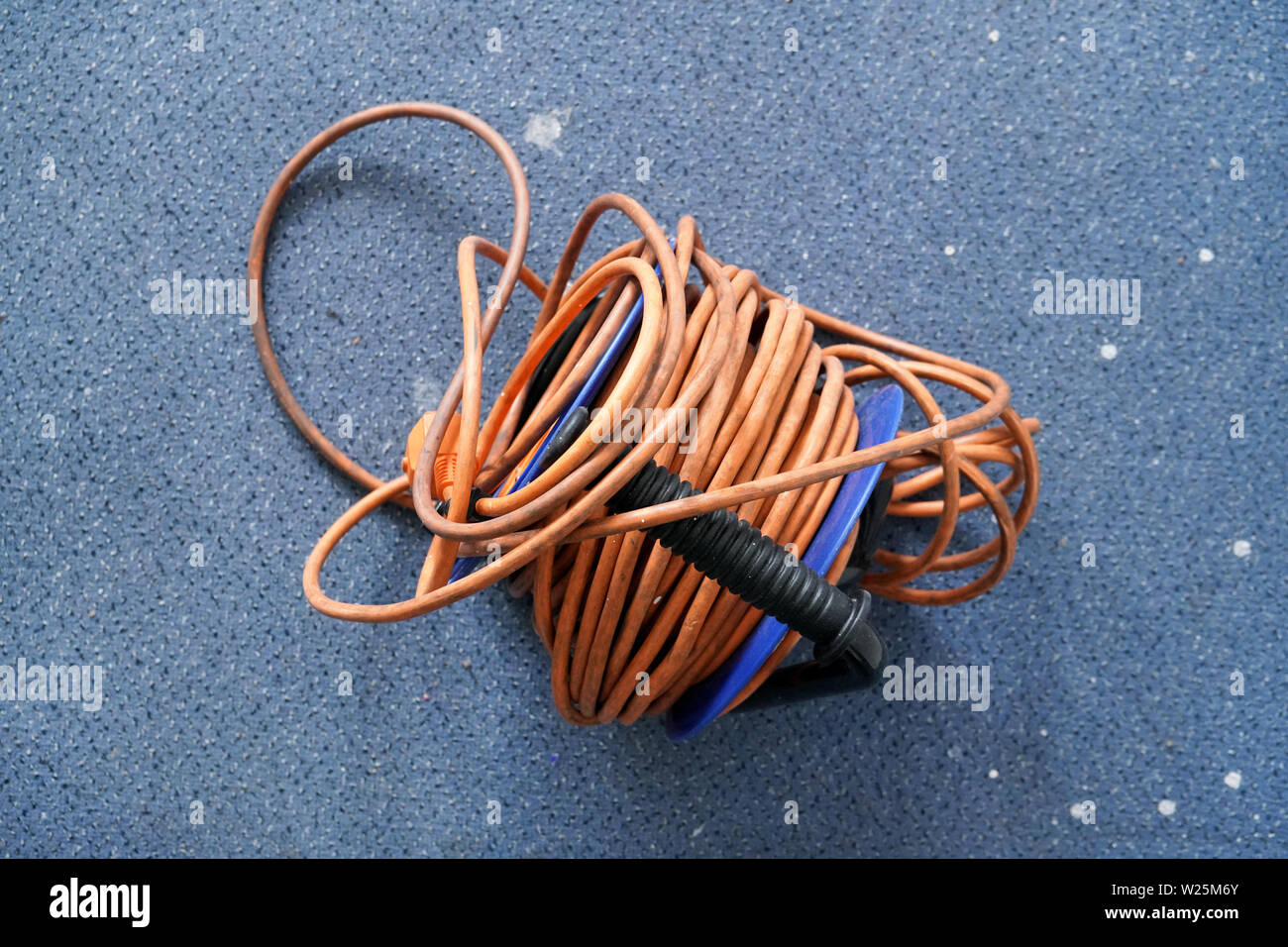 Top Down View Tangled Orange Power Cord Extension Lead On Blue Roll 
