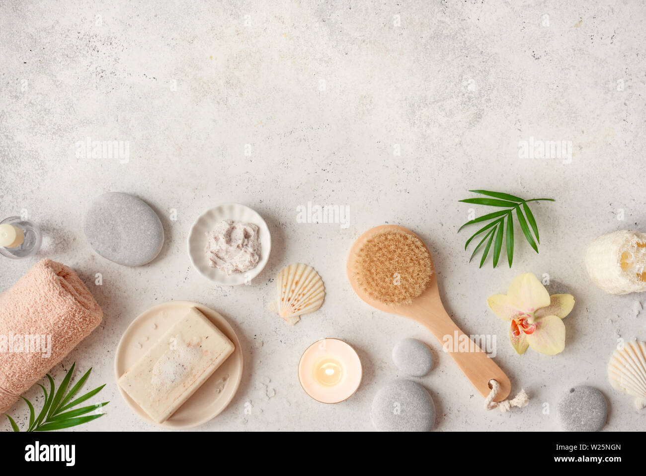 Spa concept, flat lay on white stone background, palm leaves, flower, candle and zen like grey stones, top view. Stock Photo