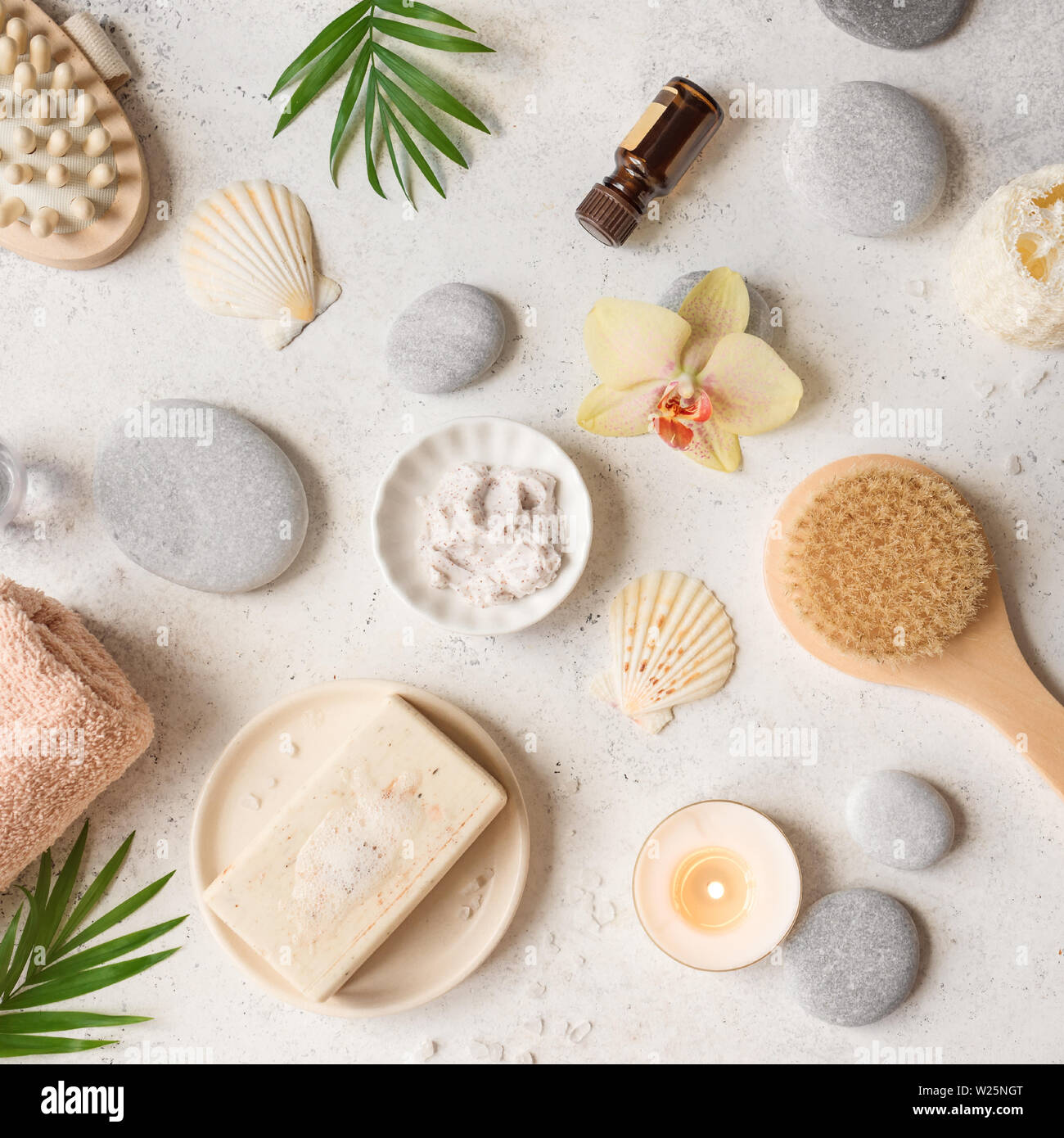 Spa concept, flat lay on white stone background, palm leaves, flower, candle and zen like grey stones, top view. Stock Photo