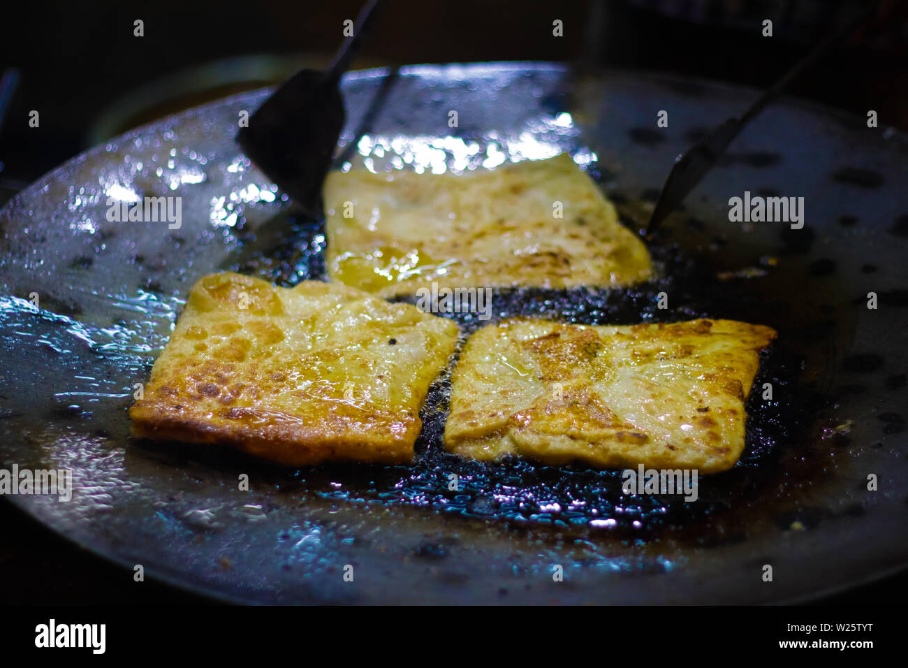 mughlai paratha, an indian street fast food is being fried in oil in a frying pan. Stock Photo