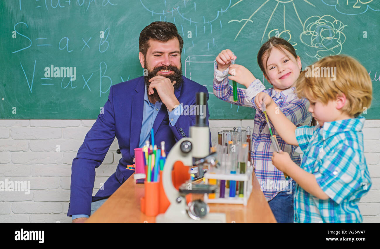 happy children teacher. back to school. biology education. Microscope. Biology school laboratory equipment. experimenting with chemicals or microscope. Enthusiastic teacher helping children Stock Photo