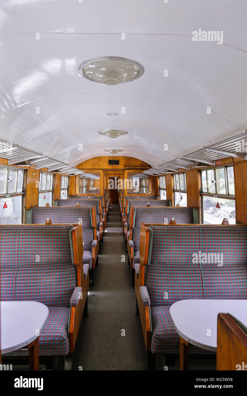 Inside a vintage railway carriage with lots of wood, upholstered seats and tables. Stock Photo
