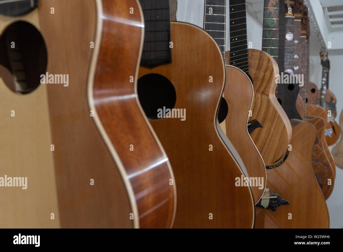 Some unfinished customed guitars and ukuleles hanging on finishing room at classical guitar workshop owned by I Wayan Tuges. Stock Photo