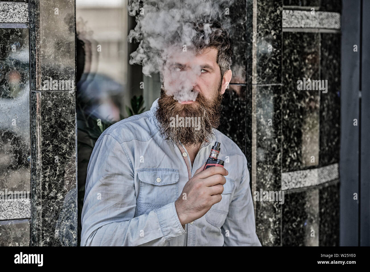 Bearded man smoking vape. Man with beard breathe out smoke. Clouds of  flavored smoke. Smoking electronic cigarette. Stress relief concept. Smoking  device. Man long beard relaxed with smoking habit Stock Photo -