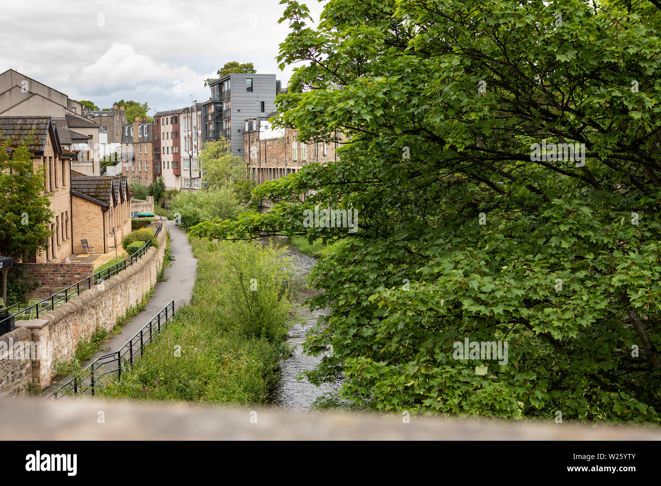 view down a bridge in Stockbridge, Edinburgh to the Water of Leith, with lush trees and a pathway Stock Photo