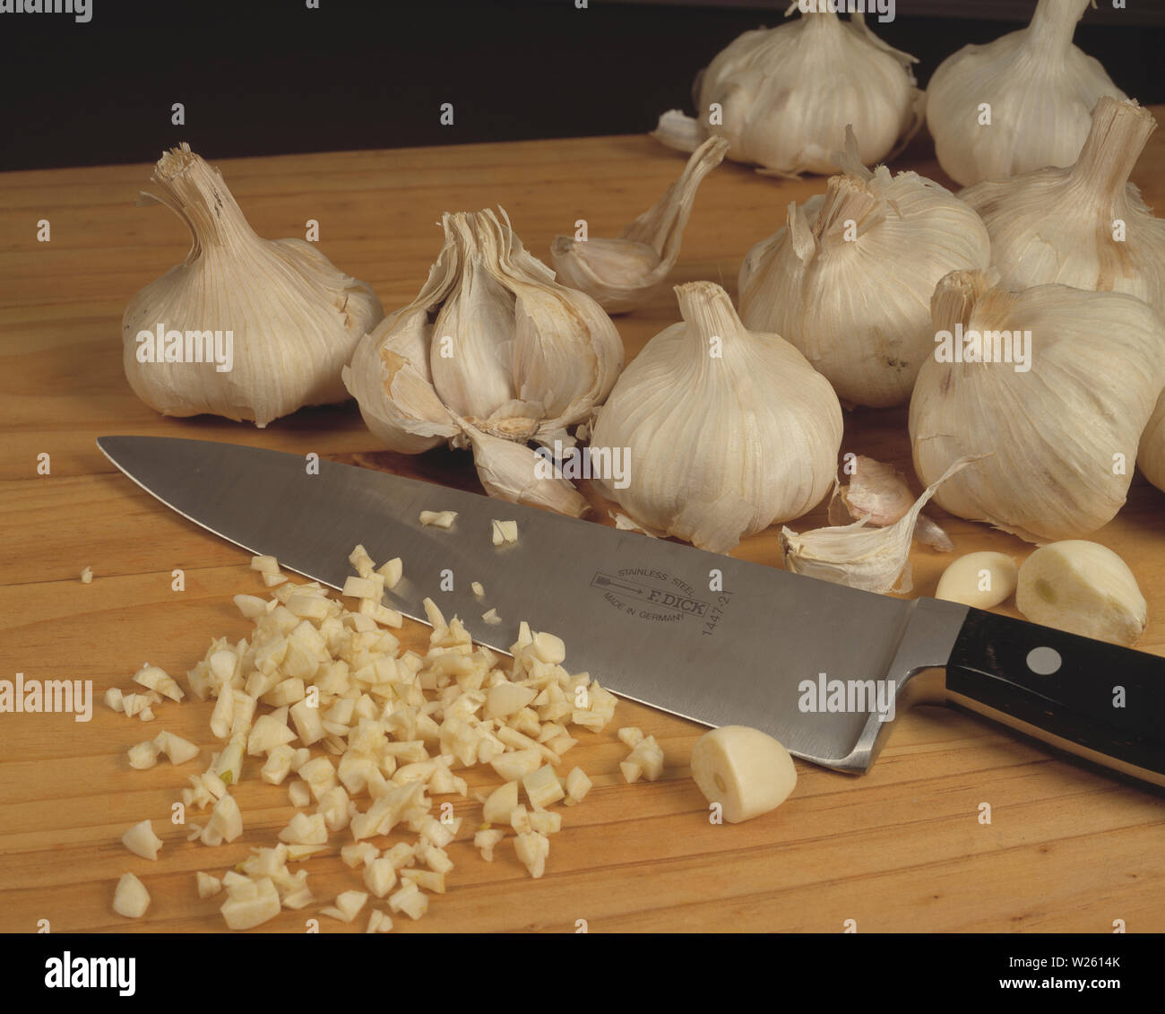 Still life.  Food. Fresh garlic cloves on chopping board with kitchen knife. Stock Photo