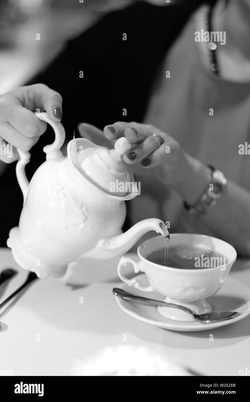 A woman pours tea into a cup. Stock Photo
