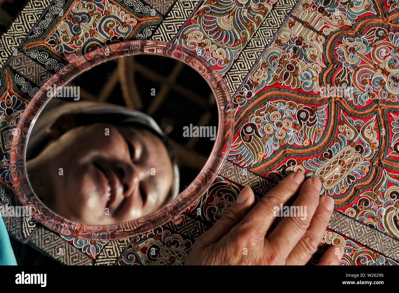 Sandu, China. 06th July, 2019. Wei Taohua, an embroiderer of the Shui ethnic group, examines a piece of finished horse tail embroidery in Sandu Shui Autonomous County, southwest China's Guizhou Province, July 6, 2019. Unlike many other embroidery styles, the horse tail embroidery of the Shui people in southwest China is characterized by unique prefabricated sewing threads made up of horse tail fibers wound with silk yarns from the outside. Credit: Xinhua/Alamy Live News Stock Photo