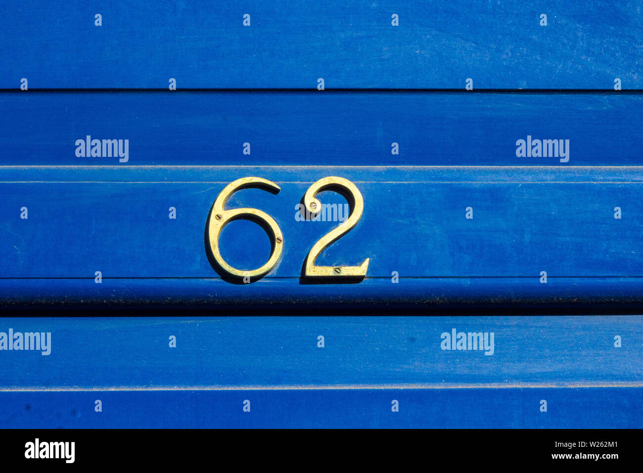 House number 62 with the sixty-two in metal digits on a bright blue wooden front door Stock Photo