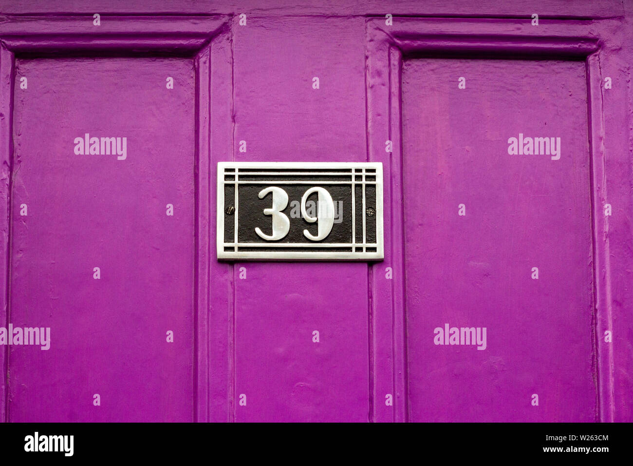 House number 39 with the thirty-nine on an art deco plaque on a purple wooden front door Stock Photo