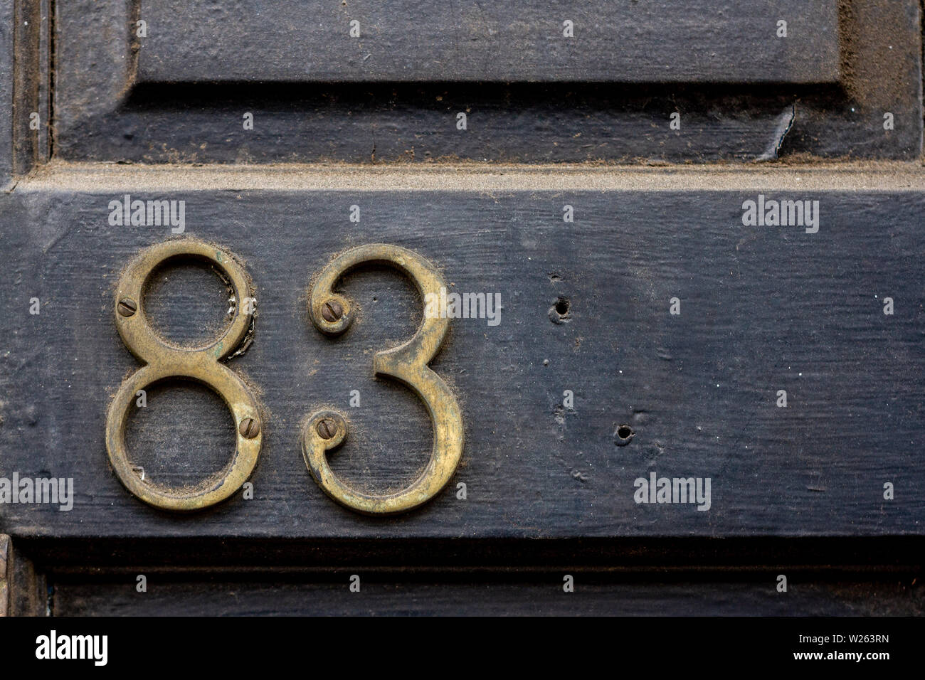 House number 83 with the eighty-three in metal digits on a wooden front door Stock Photo