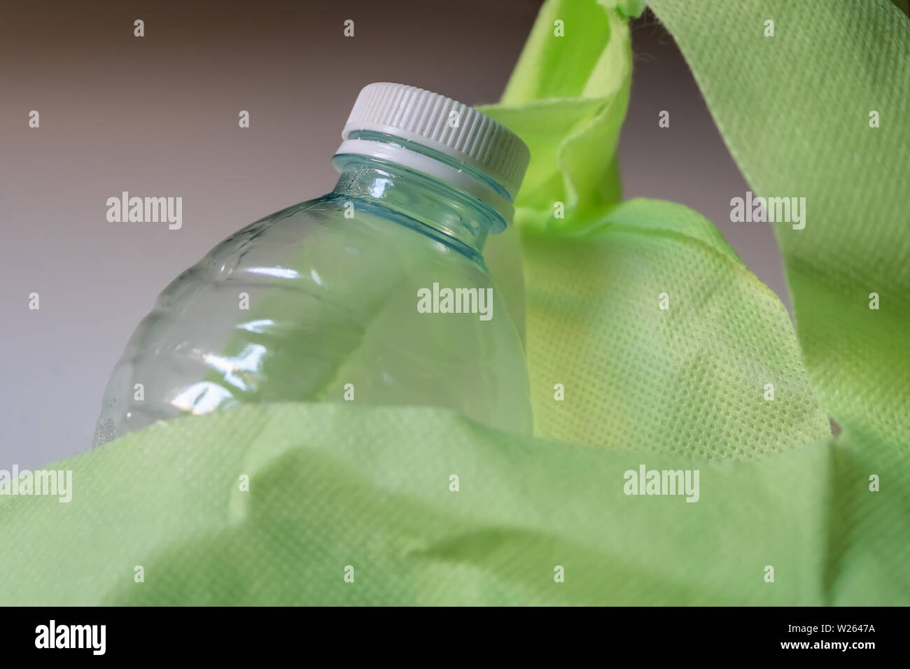 Plastic bottle with the cap inside the reusable green shopping bag closeup - Image Stock Photo