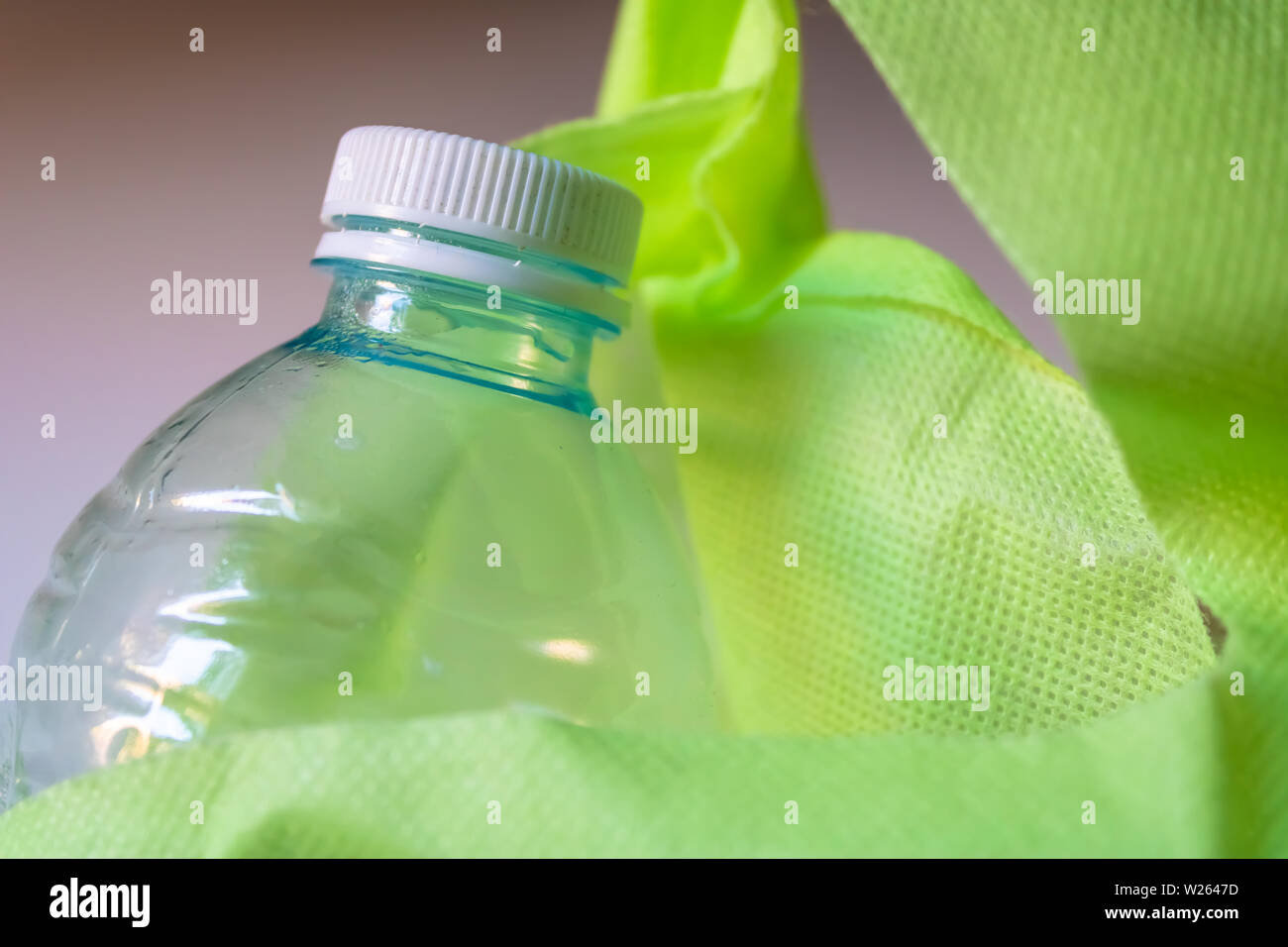 Plastic bottle with the cap inside the reusable green shopping bag - Image Stock Photo