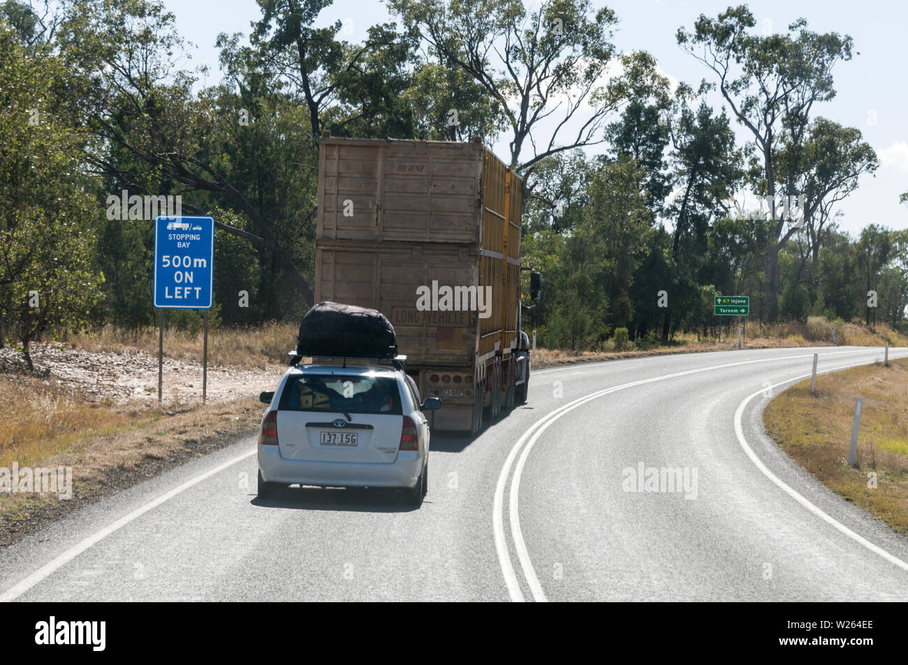 A car following a cattle road train on the Carnarvon Highway in western Queensland, Australia. Stock Photo