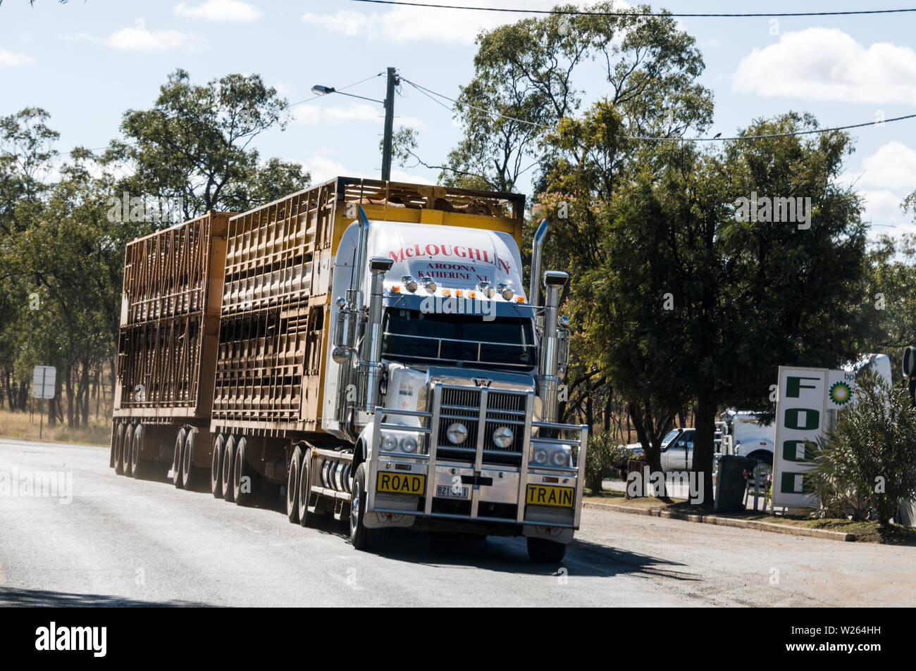 A cattle road train in beef farming country, passing a small rural town of Injune on the Carnarvon Highway in western Queensland, Australia Stock Photo