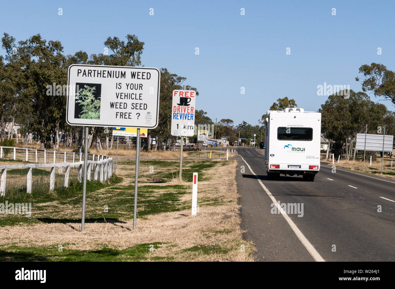 A campervan on the Carnarvon Highway, arriving in Injune, a beef farming town in Queensland, Australia.   A road sign reads, Parthenium weed is a non- Stock Photo