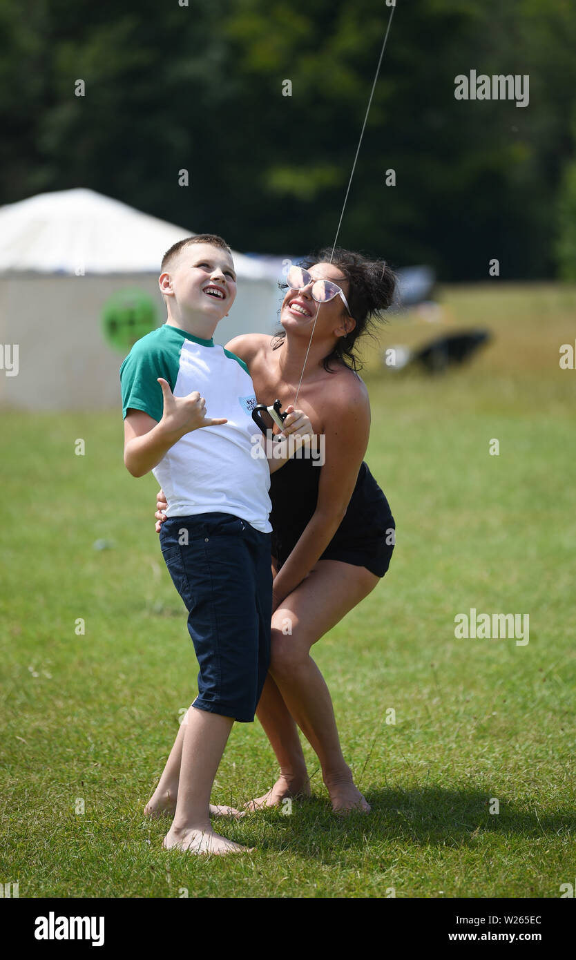 Brighton UK 6th July 2019 - A young woman and her son fly their kite on a beautiful sunny day at the start of the annual Brighton Kite Festival held in Stanmer Park and continues over the weekend . The wind conditions were poor at the start of the day but picked up in the afternoon as kite flying enthusiasts from around the world took part along with members of the public . Credit: Simon Dack / Alamy Live News Stock Photo