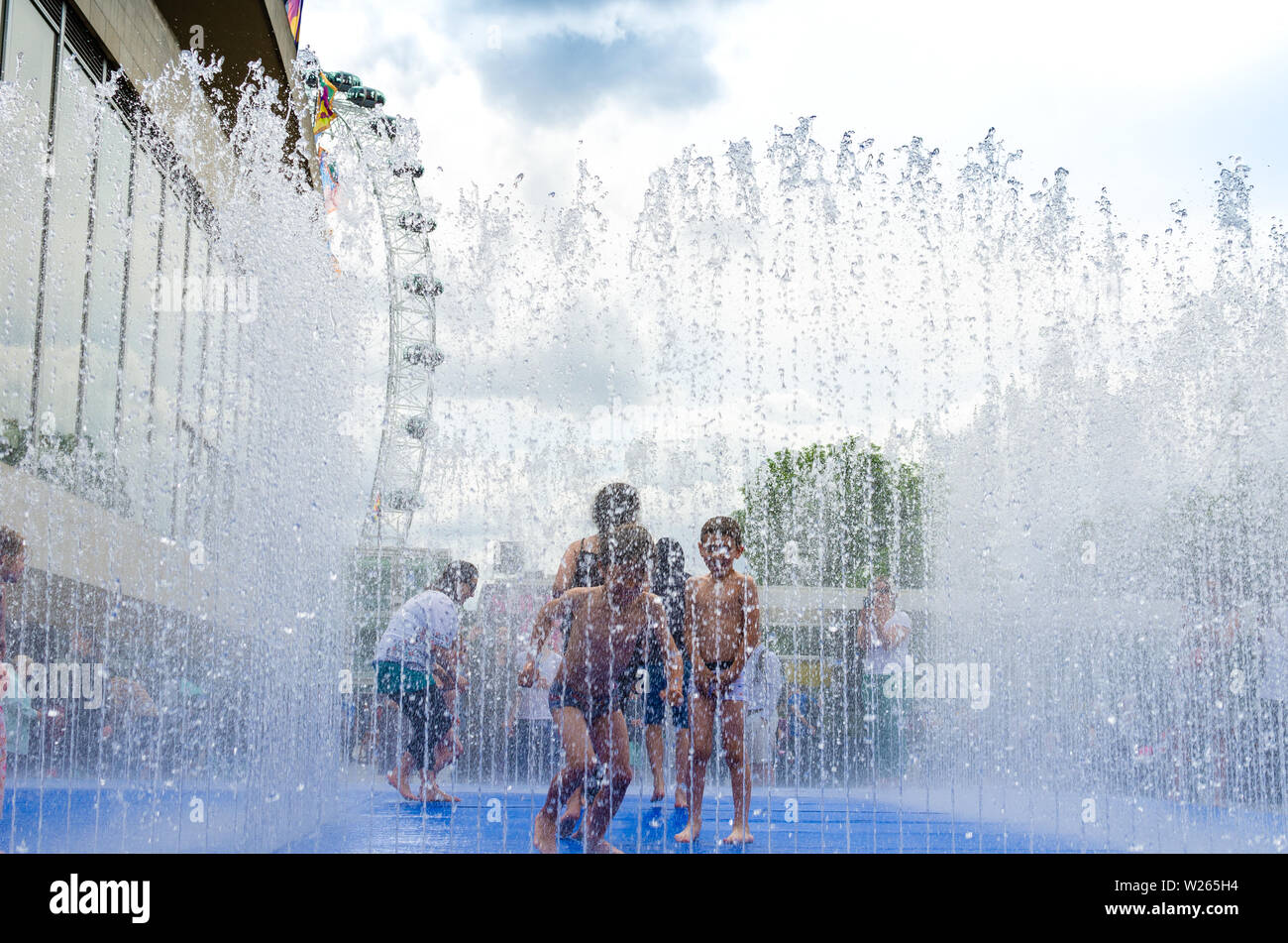 Family fun inside a street fountain during the summer heatwave in London, England Stock Photo