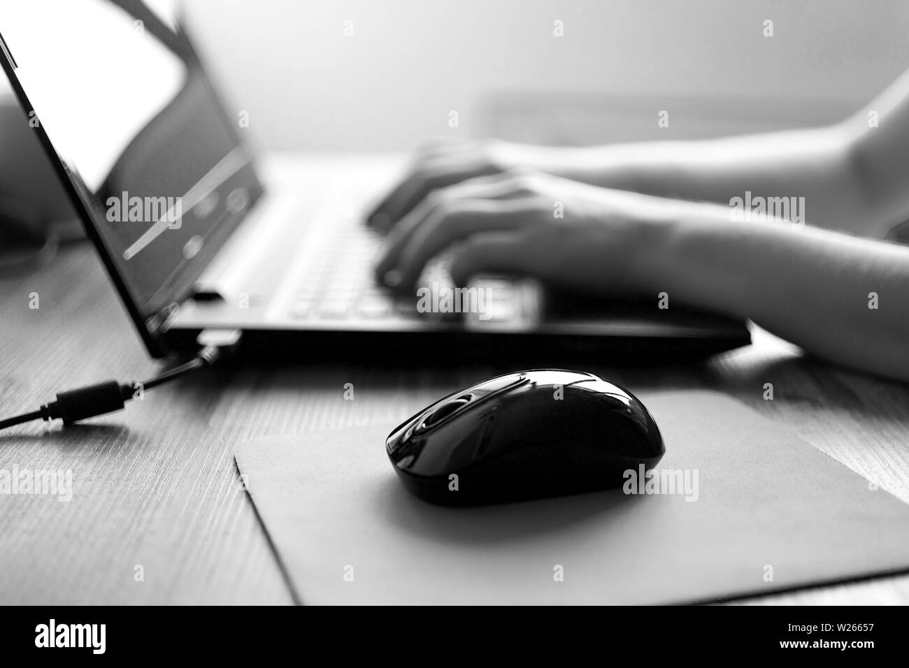 Hands typing on laptop computer keyboard, black and white Stock Photo