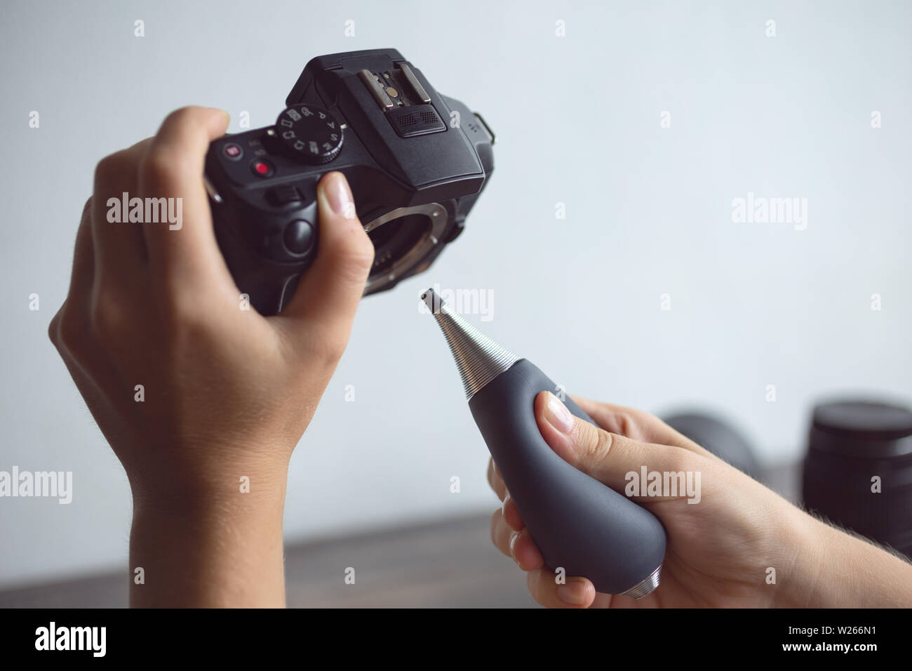 Two hands cleaning digital camera sensor from dust with air blower