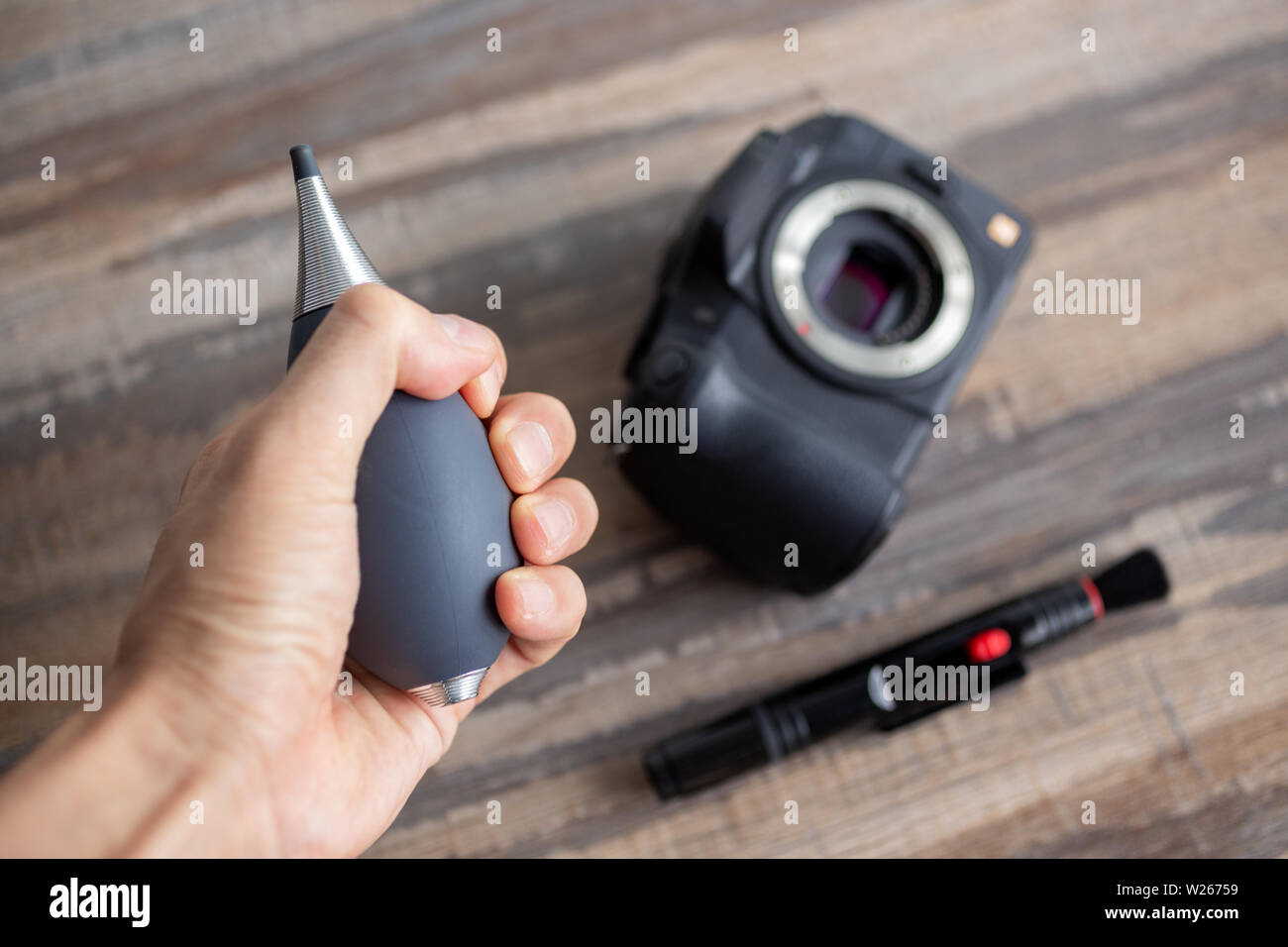 Hand cleaning digital camera sensor from dust with air blower and brush