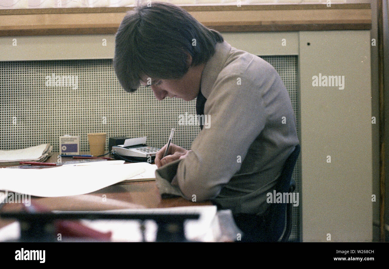 1970s, historical, a man working in an office, at a desk, in the finance department, possibly an accountant as he is using a calculator, England, UK. Stock Photo