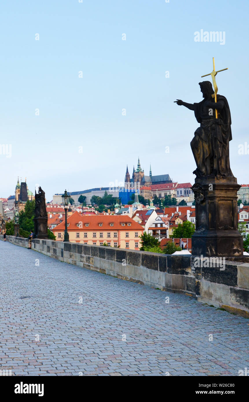 Vertical picture of Charles Bridge in Prague, Bohemia, Czech Republic taken in the early morning in sunrise light with almost no people. Prague Castle in background. Tourist attraction. Stock Photo