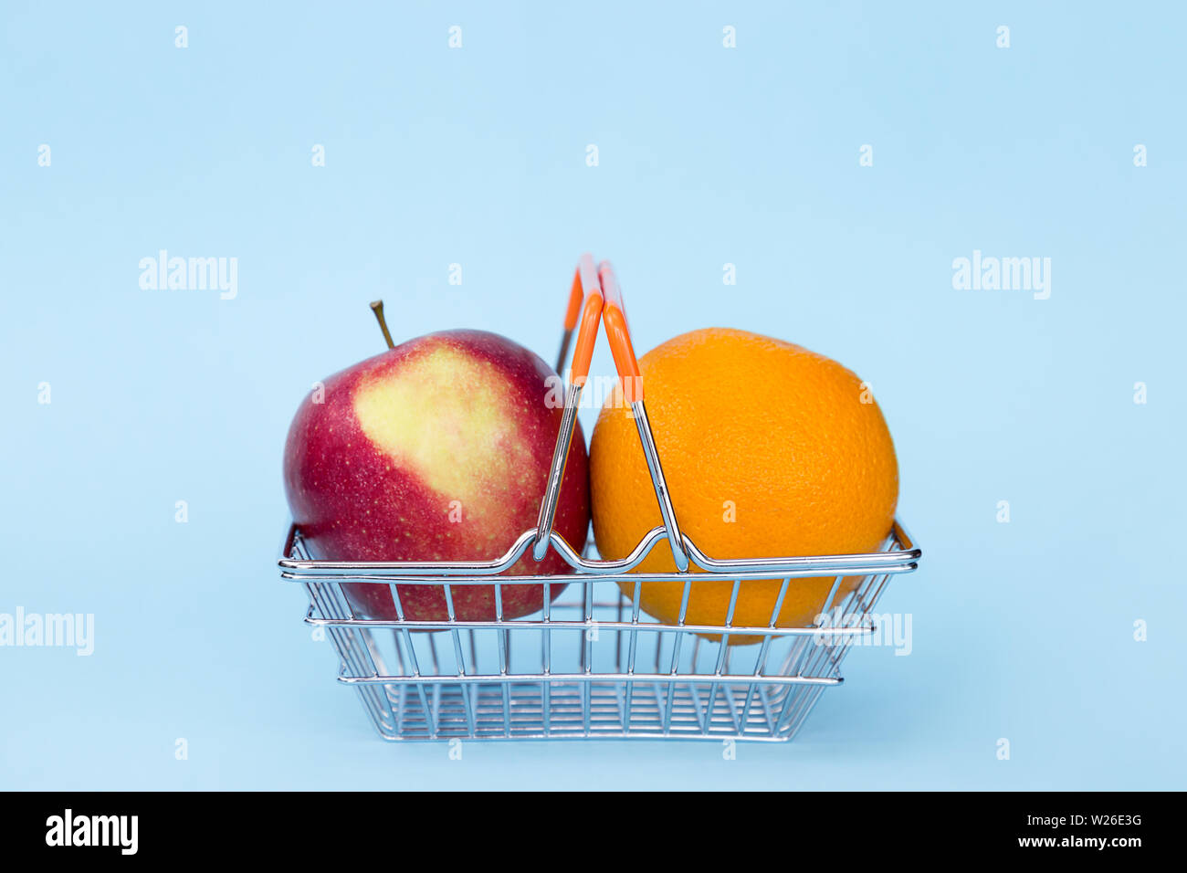 red apple and orange in cart on blue color background Stock Photo